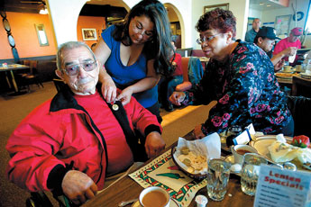 Tina Cordova, center, fastens a medal to World War II veteran Onesimo Rios as his wife Helen, right, looks on. Rios received his service medals while being honored by Gallup mayor Jackie McKinney at Don Diego's Restaurant on Friday. 2011 Gallup Independent / Adron Gardner 